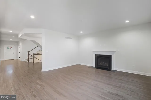 a view of an empty room with wooden floor and windows