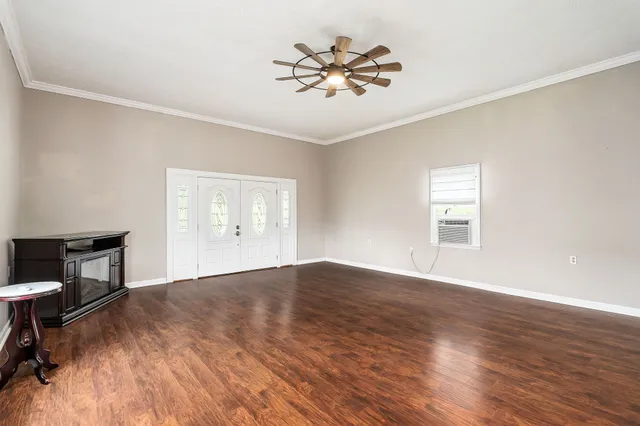 a view of an empty room with a window and wooden floor
