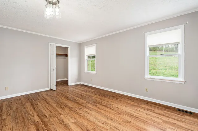 a view of an empty room with wooden floor and a window