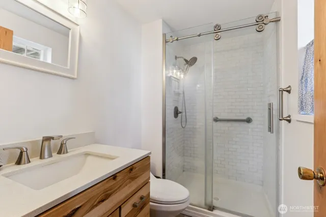 a bathroom with a granite countertop sink toilet a mirror and shower