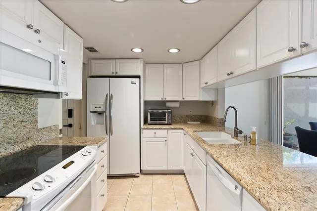 a kitchen with a refrigerator a sink and white cabinets