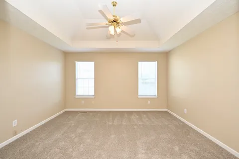 an empty room with windows and ceiling fan