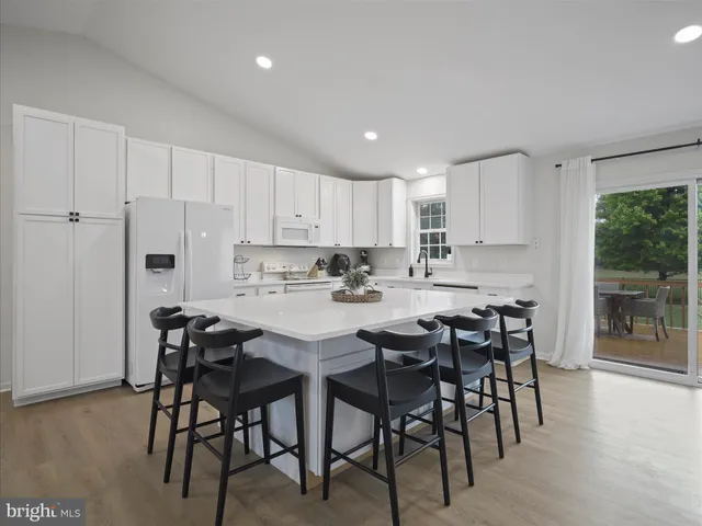 a kitchen with stainless steel appliances granite countertop a table chairs refrigerator sink and cabinets