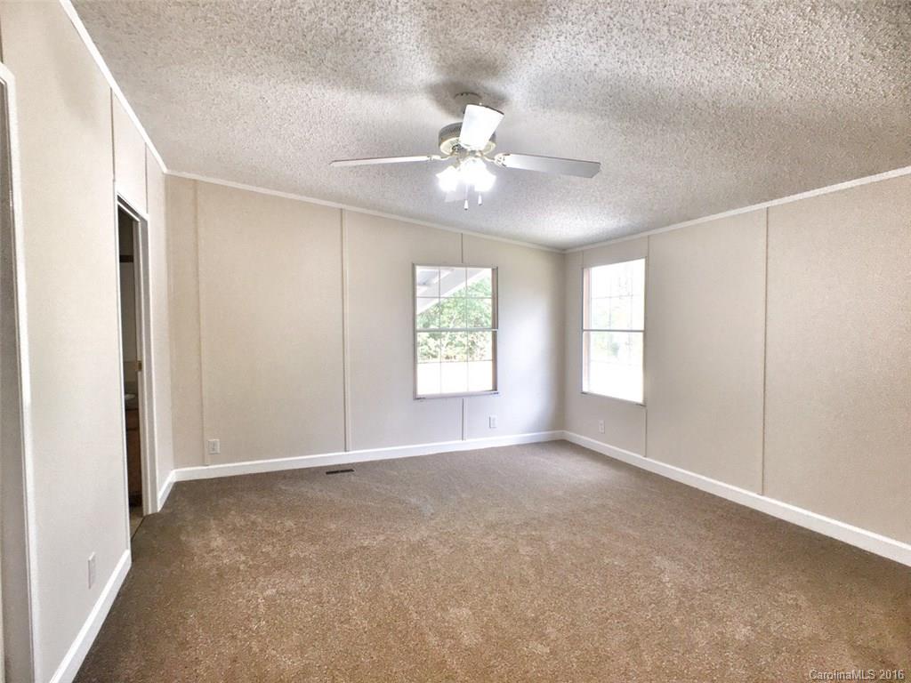 5563 South Wilson Hill Road Mill Spring, NC 28756 - Photo 14 of 18 an empty room with windows and ceiling fan