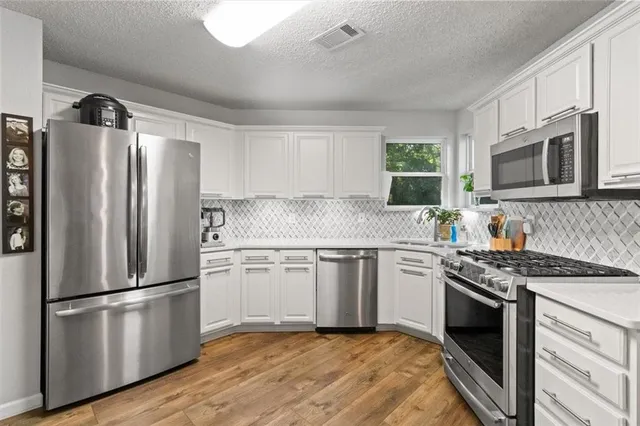 a kitchen with granite countertop stainless steel appliances a sink cabinets and a window