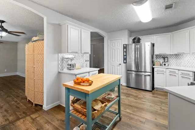 a kitchen with stainless steel appliances granite countertop a refrigerator a sink dishwasher and a stove with wooden floor