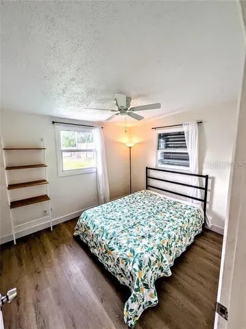 a bed sitting in a bedroom next to a window with wooden floor
