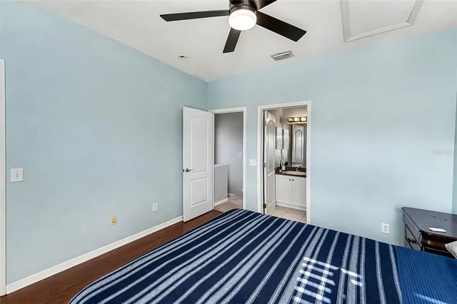 a view of an empty room with wooden floor and a ceiling fan