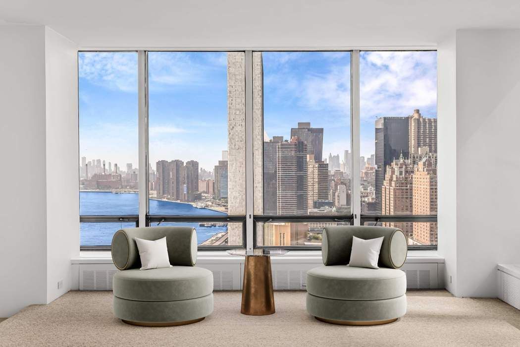 870 United Nations Plaza, Unit 28A Manhattan, NY 10017 - Photo 1 of 28 a living room with furniture and a large window