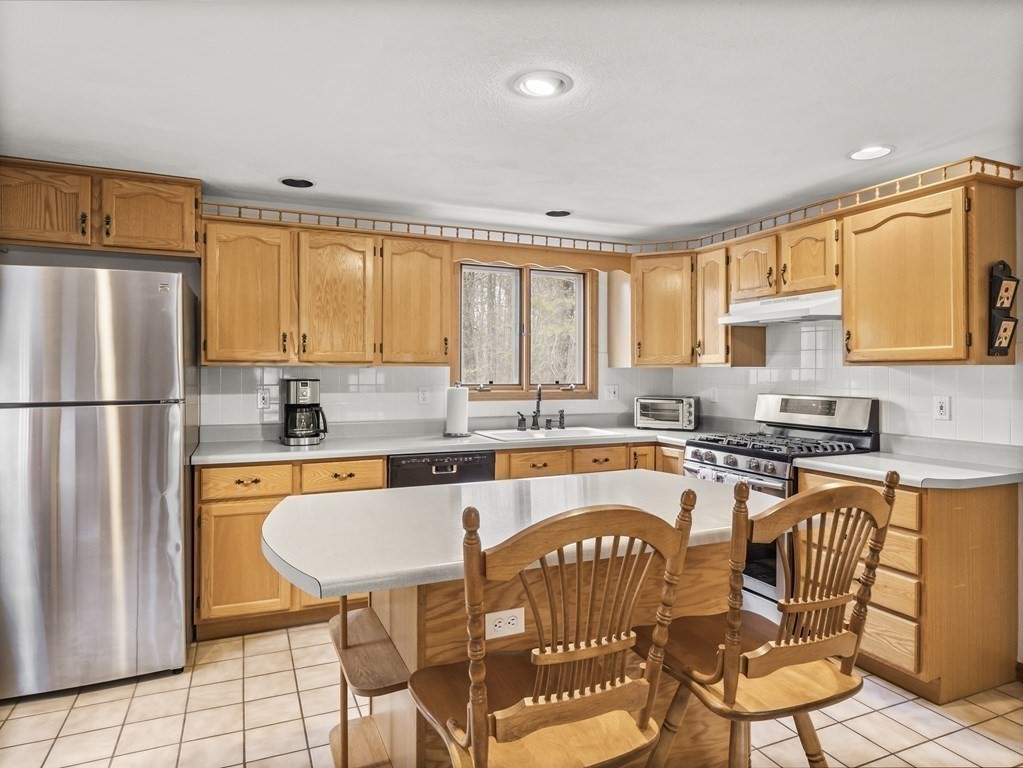 17 Chestnut Road Tyngsboro, MA 01879 - Photo 11 of 41 a kitchen with stainless steel appliances granite countertop a stove a sink a refrigerator a dining table and chairs