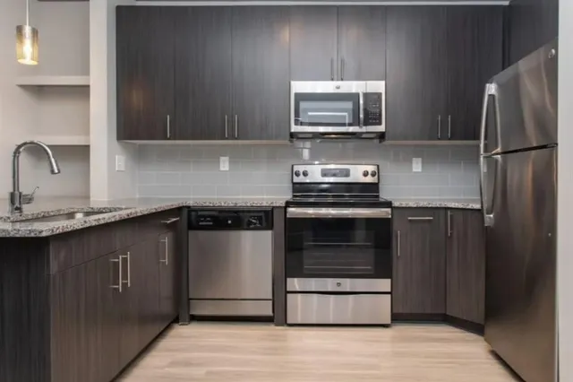 a kitchen with granite countertop a refrigerator and a stove top oven