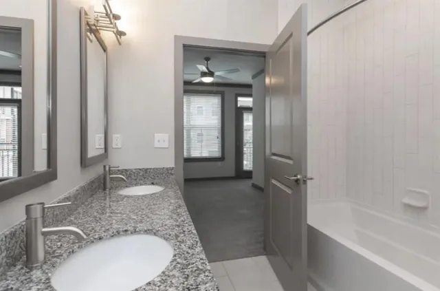 a bathroom with a granite countertop sink a mirror and a bathtub