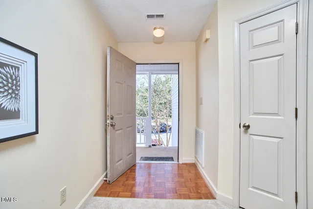 a view of a hallway with wooden floor and a bathroom