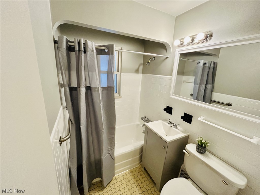 13414 Rockside Road Garfield Heights, OH 44125 - Photo 12 of 25 Full bathroom with toilet, shower / bathtub combination with curtain, tile walls, vanity with extensive cabinet space, and tile floors