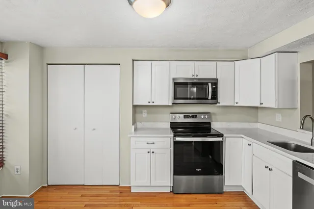 a kitchen with granite countertop white cabinets and stainless steel appliances