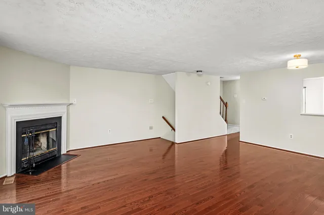an empty room with wooden floor fireplace and windows
