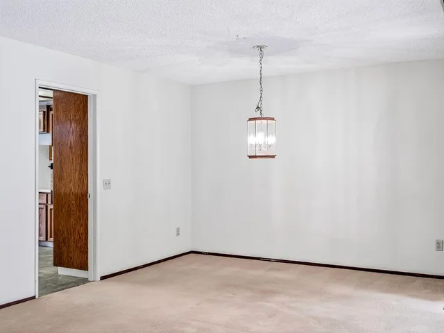 a view of a room with a hanging light and kitchen view