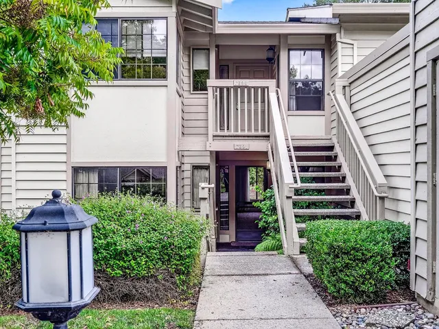 a view of a brick house with plants and large tree