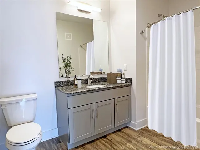 a bathroom with a granite countertop toilet sink and mirror