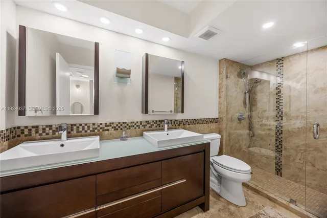 a bathroom with a double vanity sink toilet mirror and shower