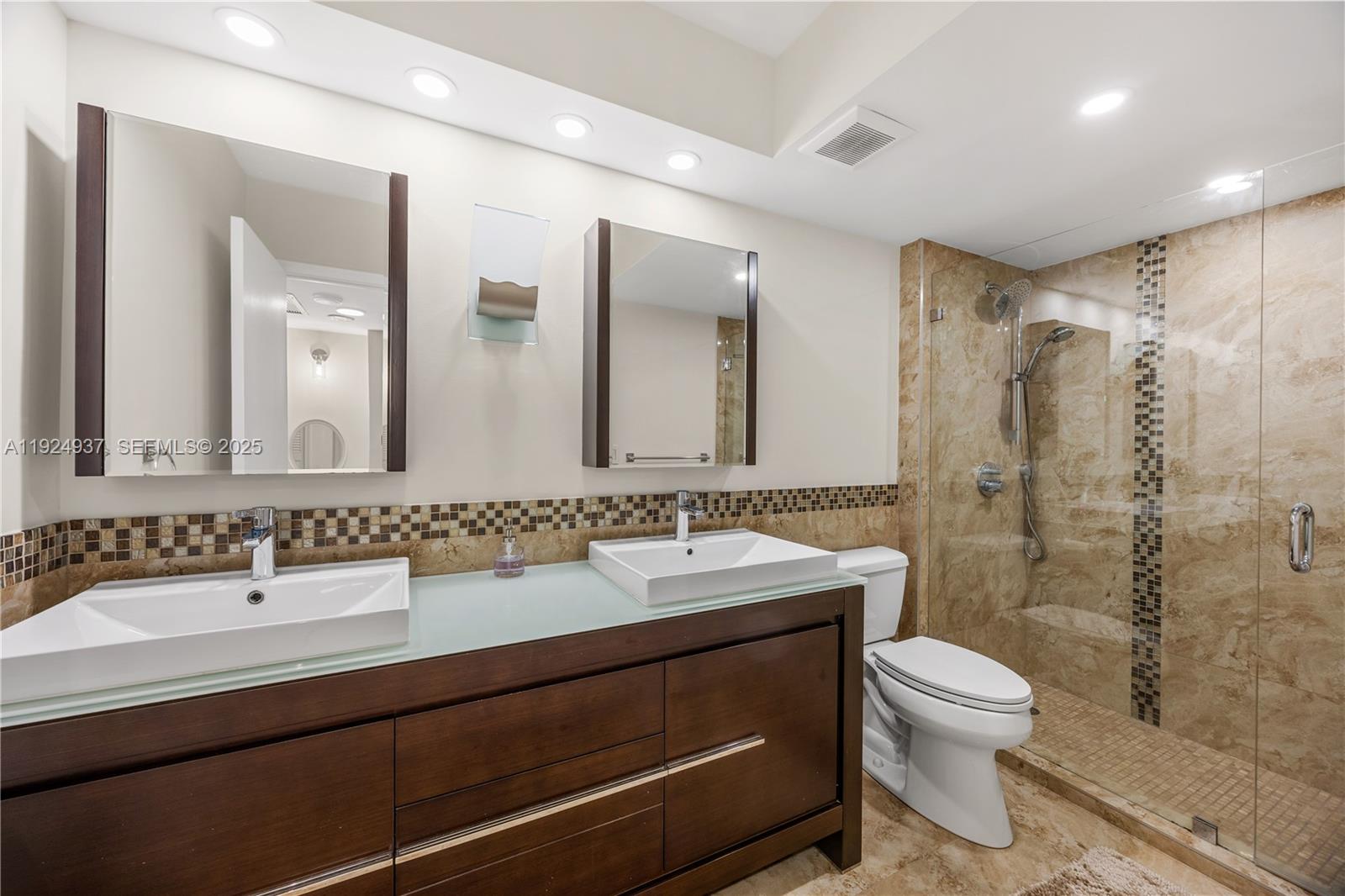 9801 Collins Avenue, Unit 10G Bal Harbour, FL 33154 - Photo 31 of 34 a bathroom with a double vanity sink toilet mirror and shower