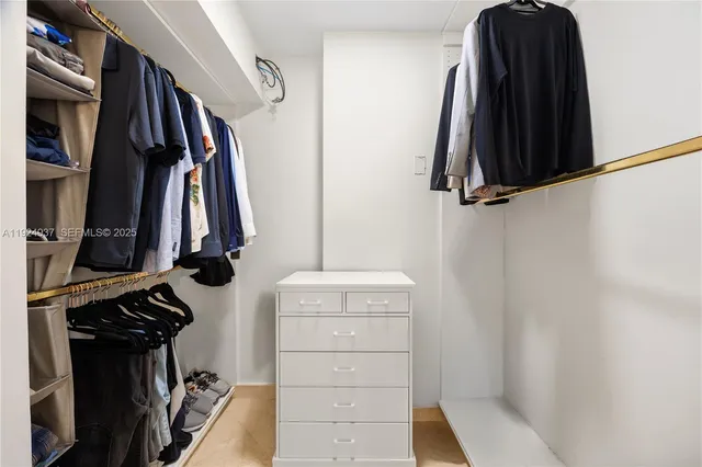 a view of walk in closet with clothes and shoes