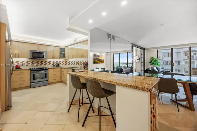 a kitchen with stainless steel appliances granite countertop table chairs sink and cabinets