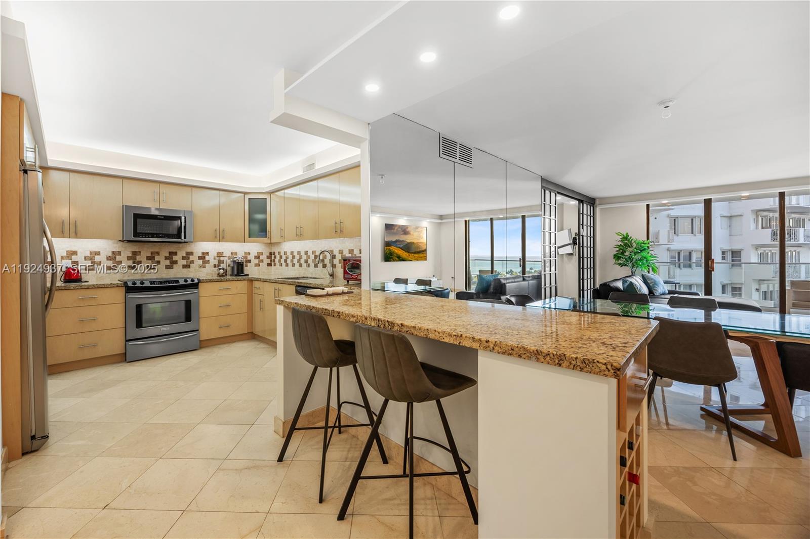 9801 Collins Avenue, Unit 10G Bal Harbour, FL 33154 - Photo 8 of 34 a kitchen with stainless steel appliances granite countertop table chairs sink and cabinets