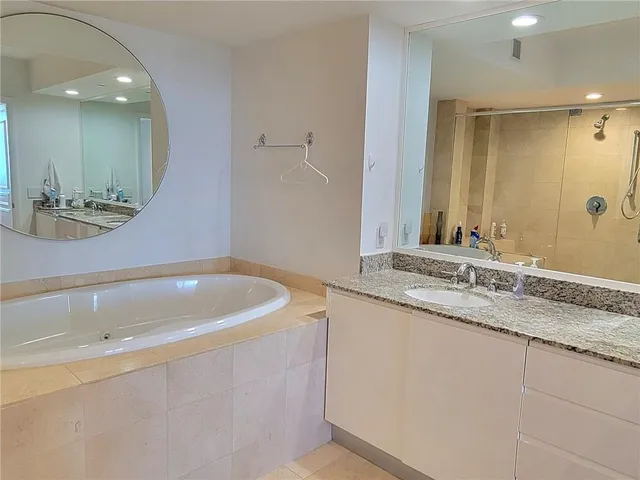 a bathroom with a tub sink and mirror