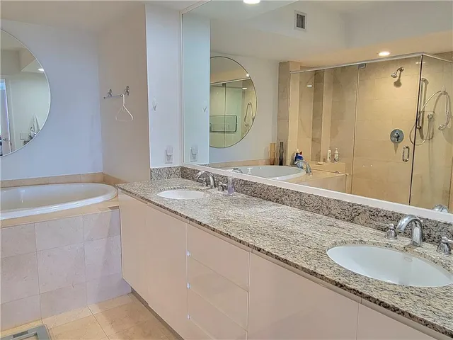 a bathroom with a granite countertop double vanity sink and a mirror