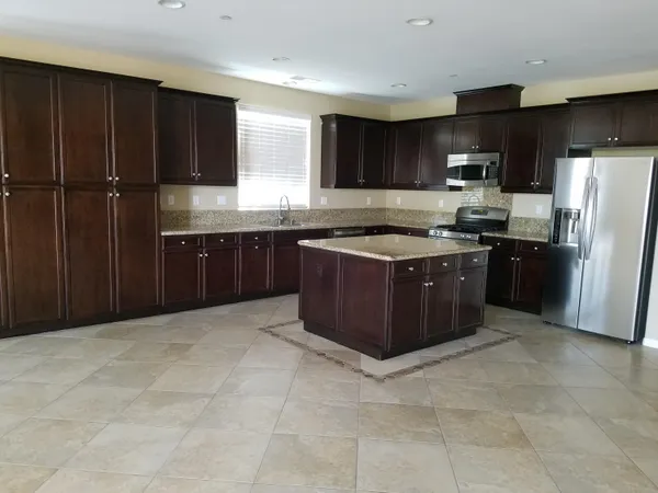 a kitchen with stainless steel appliances granite countertop a stove top oven a sink and a refrigerator