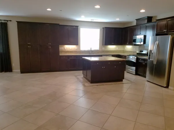 a large kitchen with granite countertop a refrigerator a stove a sink and a oven