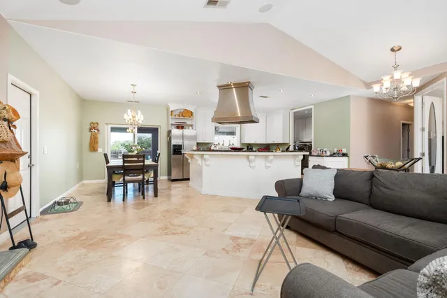a kitchen island with stainless steel appliances a table chairs and a refrigerator
