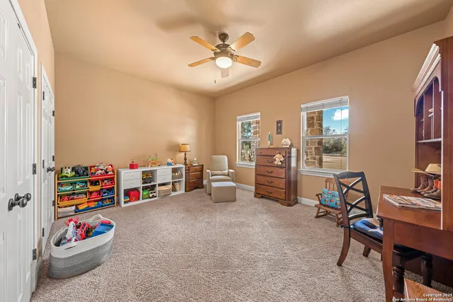 a spacious bedroom with a bed a dresser and paintings on the wall
