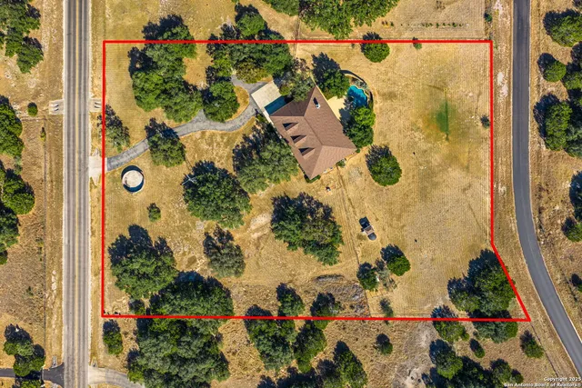 an aerial view of residential houses with outdoor space and trees all around