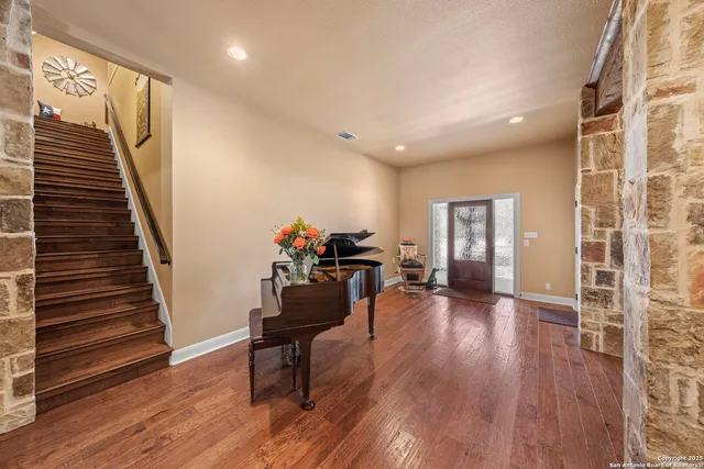 a dining hall with stainless steel appliances a dining table chairs and couches with wooden floor