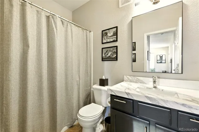 a bathroom with a granite countertop sink and a toilet