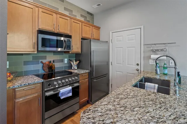 a kitchen with stainless steel appliances granite countertop a stove refrigerator and a microwave