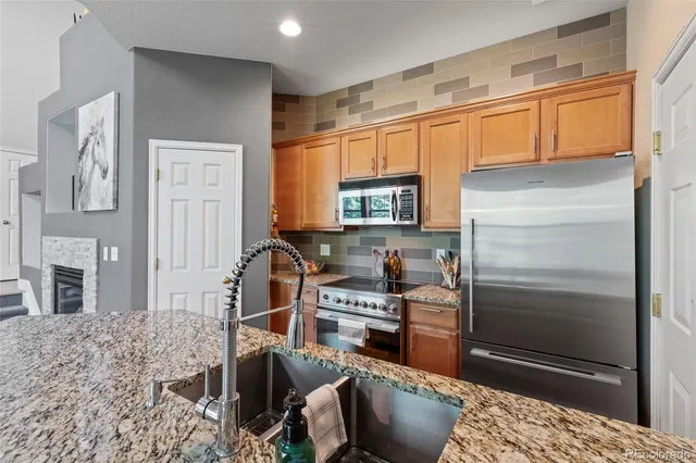 a kitchen with stainless steel appliances granite countertop a refrigerator and a stove top oven