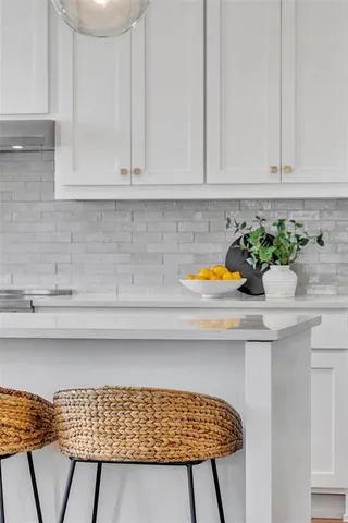 a sink with white cabinets and potted plant
