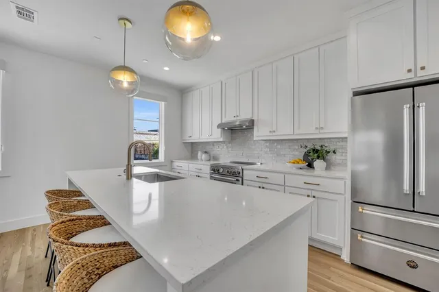 a kitchen with a refrigerator a stove cabinets and living room view