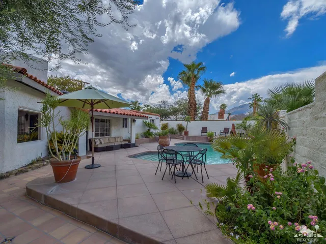 a view of a patio with table and chairs potted plants and a large tree