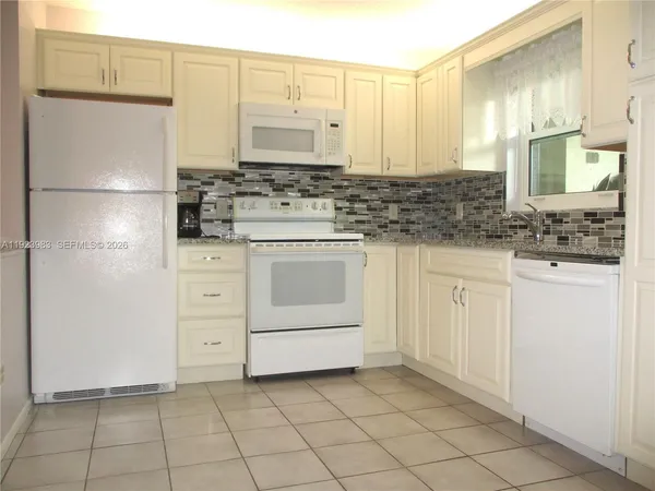 a kitchen with white cabinets and white appliances