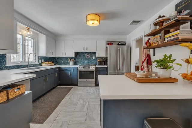 a kitchen with stainless steel appliances kitchen island granite countertop a sink a stove counter space and cabinets