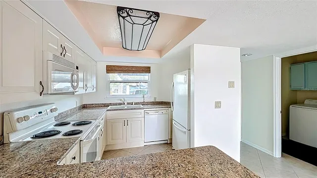 a kitchen with granite countertop white cabinets stainless steel appliances and sink