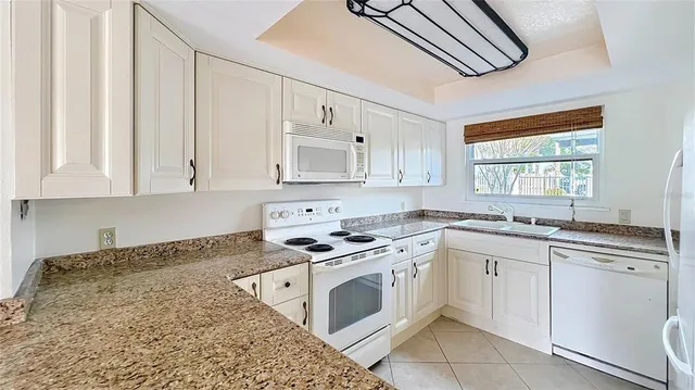 a kitchen with stainless steel appliances granite countertop white cabinets and window