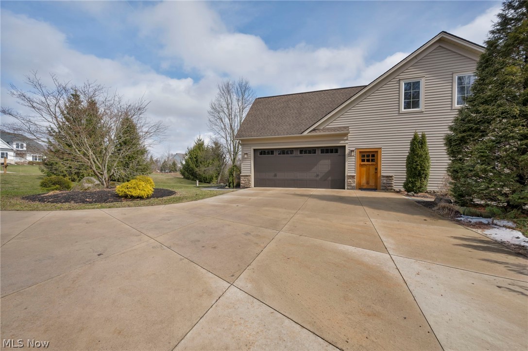 11295 Sutton Place Chardon, OH 44024 - Photo 4 of 50 View of property exterior featuring concrete driveway, roof with shingles, stone siding, and an attached garage