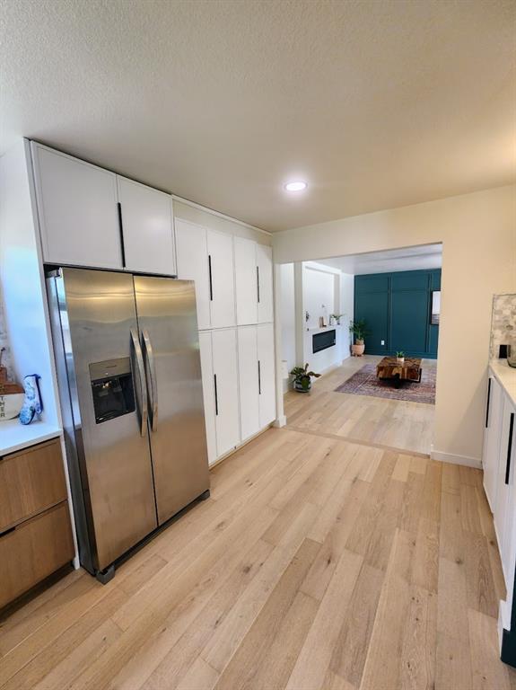 2908 Washington Street Commerce, TX 75428 - Photo 8 of 29 Kitchen featuring abundant white cabinetry with minimalist black hardware, stainless steel refrigerator, and wood-finish flooring