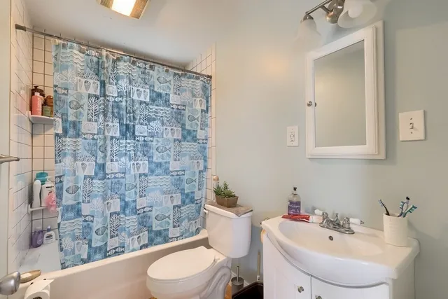 a bathroom with a sink a toilet and shower curtain