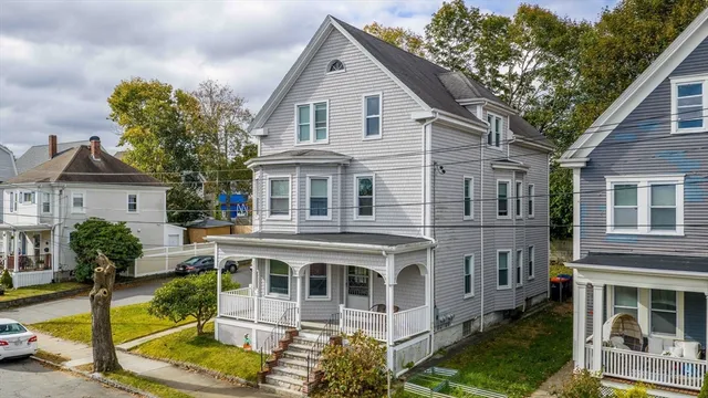 a view of a white house with large windows and a small yard